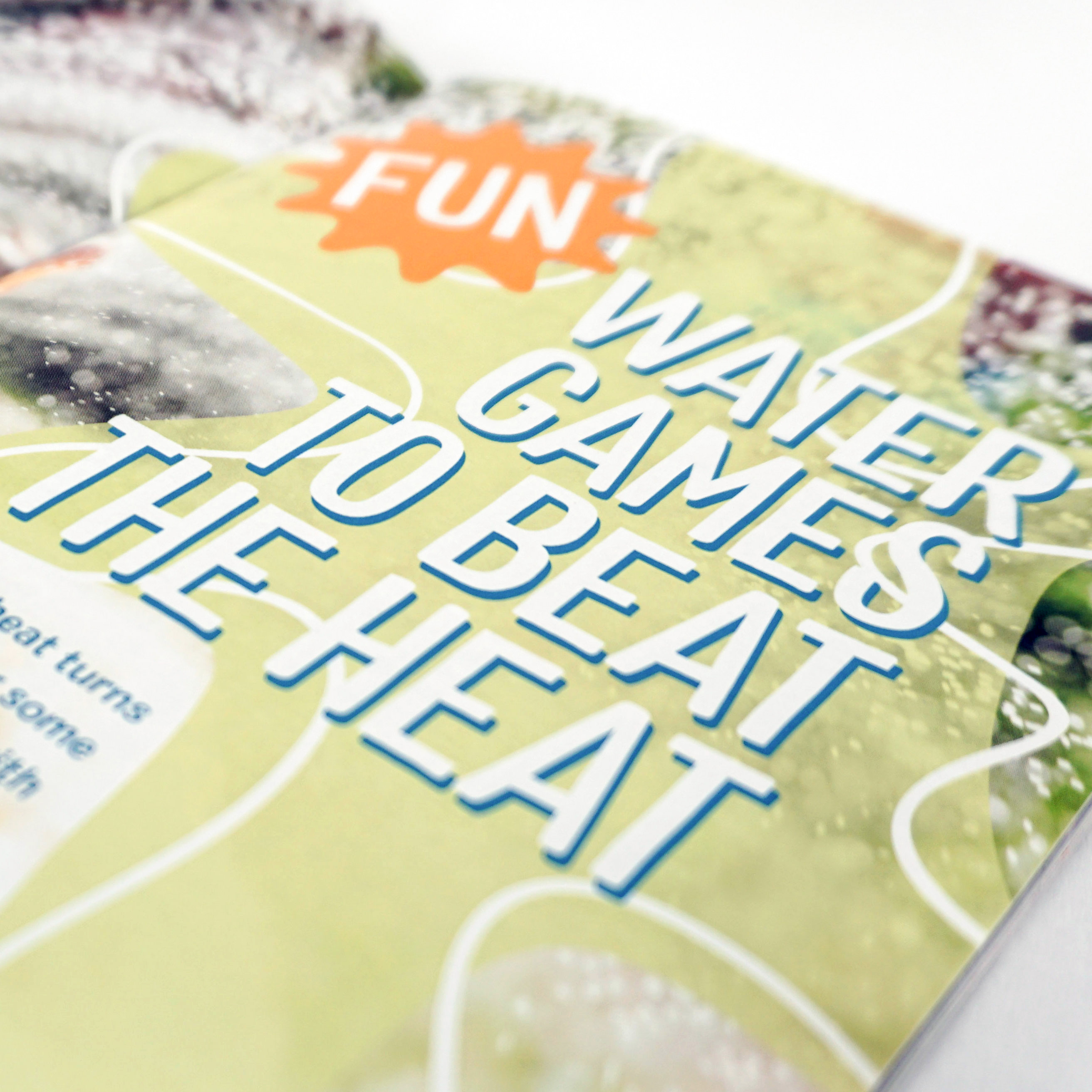 A magazine spread with a boy getting splashed while coming down a water slide. The article title reads "Fun Water Games to Beat the Heat", designed by Alexa Lasco.