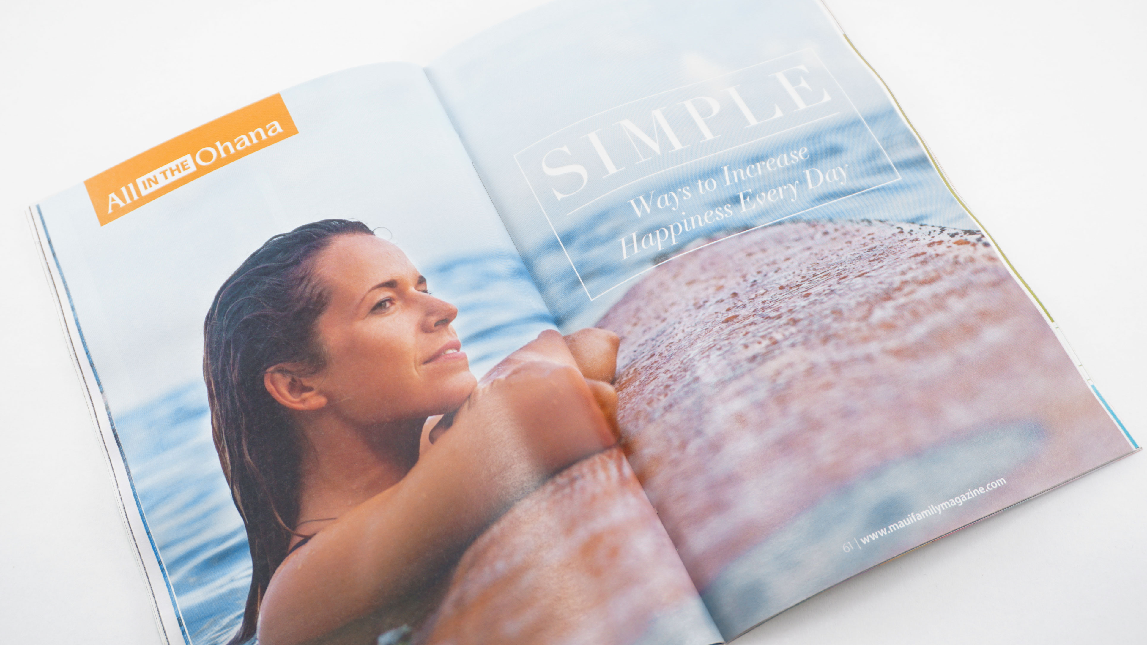 A magazine spread with a woman leaning on a surfboard in the ocean. The article title reads "Simple Ways to Increase Happiness Every Day", designed by Alexa Lasco.