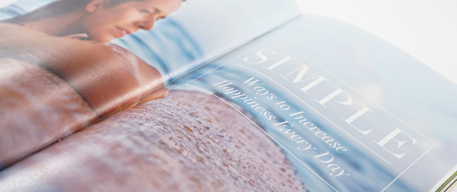 A magazine spread with a woman leaning on a surfboard in the ocean. The article title reads "Simple Ways to Increase Happiness Every Day", designed by Alexa Lasco.